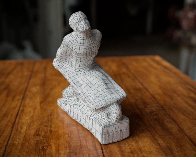 Figurka mężczyzny pchającego taczkę z nałożoną siatką wielokątów uzyskaną ze skanu 3D